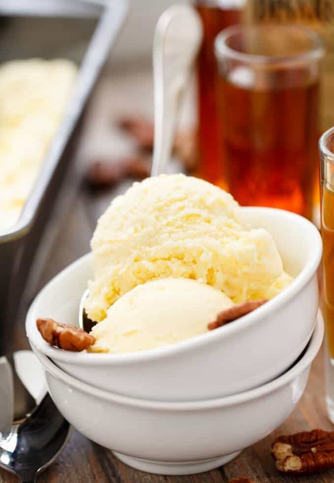 Amaretto Ice Cream in pile of white bowls with walnuts on table with spoons, walnuts glass shots