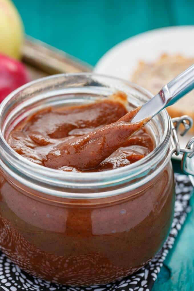 Apple butter in glass jar with knife on blue table