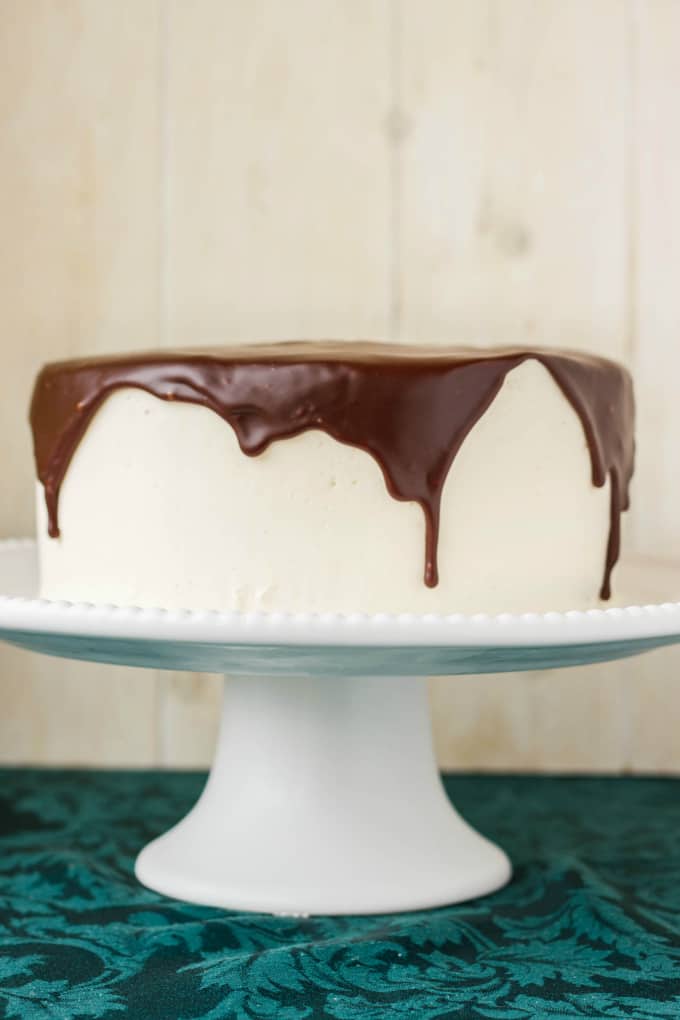 Chocolate Cake covered in Chocolate Ganache Glaze on white tray on blue table