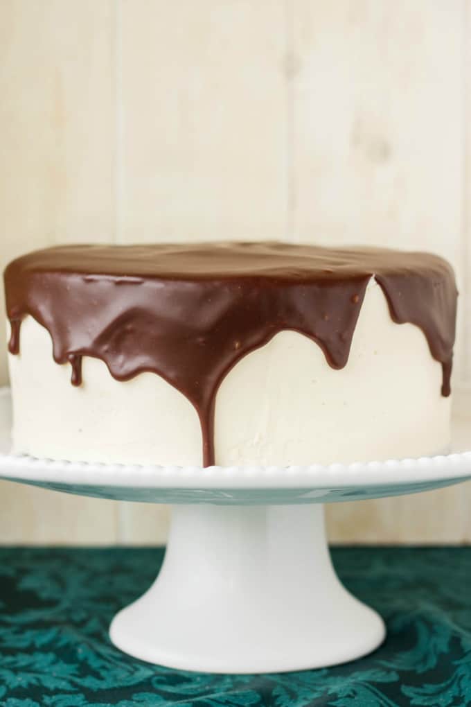 Chocolate Cake covered in Chocolate Ganache Glaze on white tray on blue table