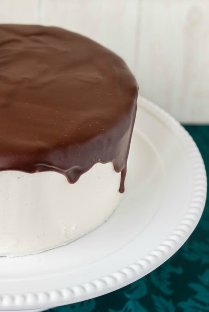 Chocolate Cake covered in Chocolate Ganache Glaze on white tray on blue table