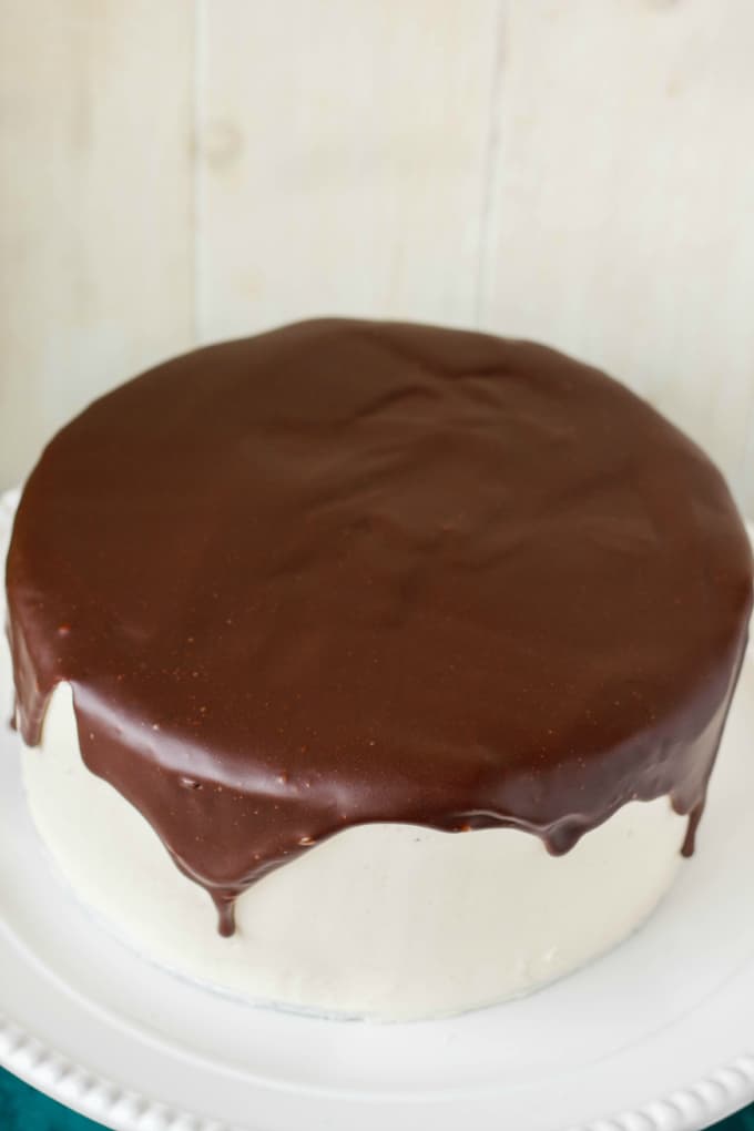 Chocolate Cake covered in Chocolate Ganache Glaze on white tray, white background