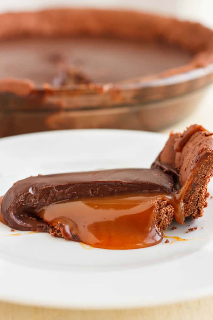 Chocolate Caramel Pie slice on white plate, rest of the cake in the background