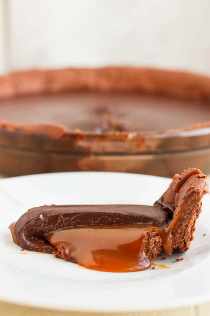 Chocolate Caramel Pie slice on white plate, rest of the cake in the background