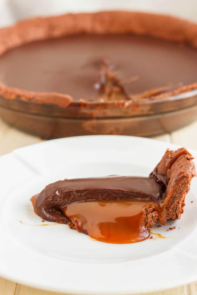 Chocolate Caramel Pie slice on white plate, rest of the cake in the background