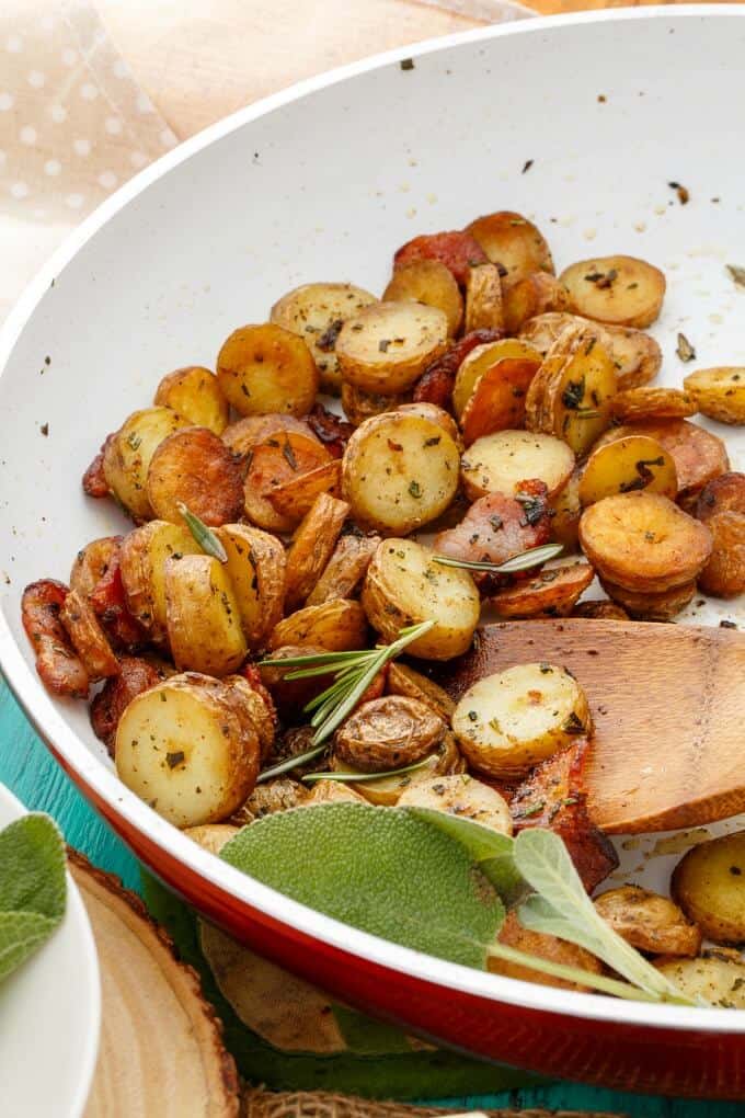 Pan-Fried Fingerling Potatoes with Bacon in pan with herbs and wooden spatula
