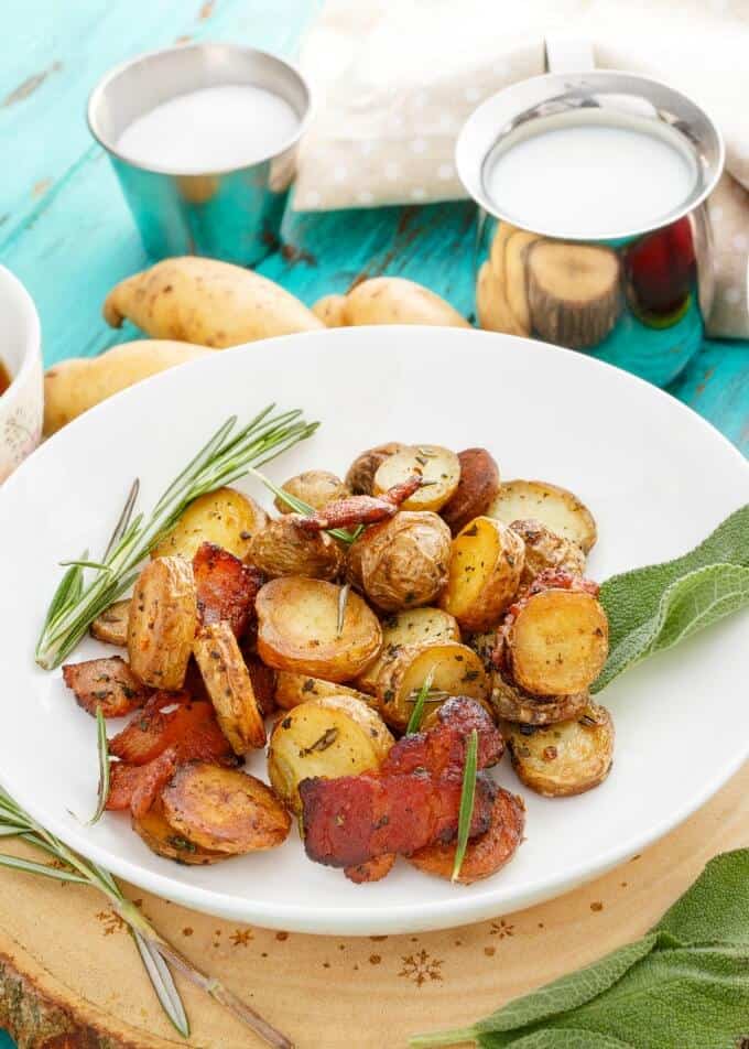 Pan-Fried Fingerling Potatoes with Bacon on white plate on blue table with bowl of sugar and milk and potatoes and veggie