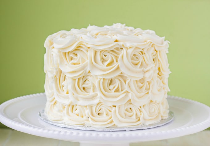 Red Velvet Cake with Vanilla Buttercream Rosettes on white tray on white table on green background