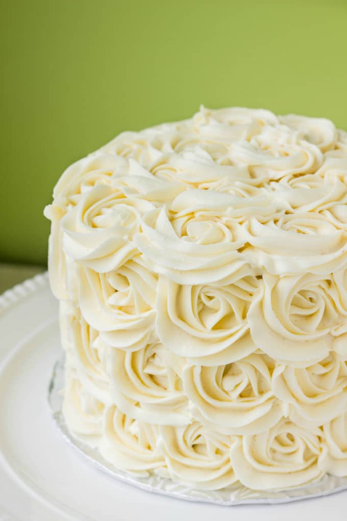 Red Velvet Cake with Vanilla Buttercream Rosettes on white tray on green background