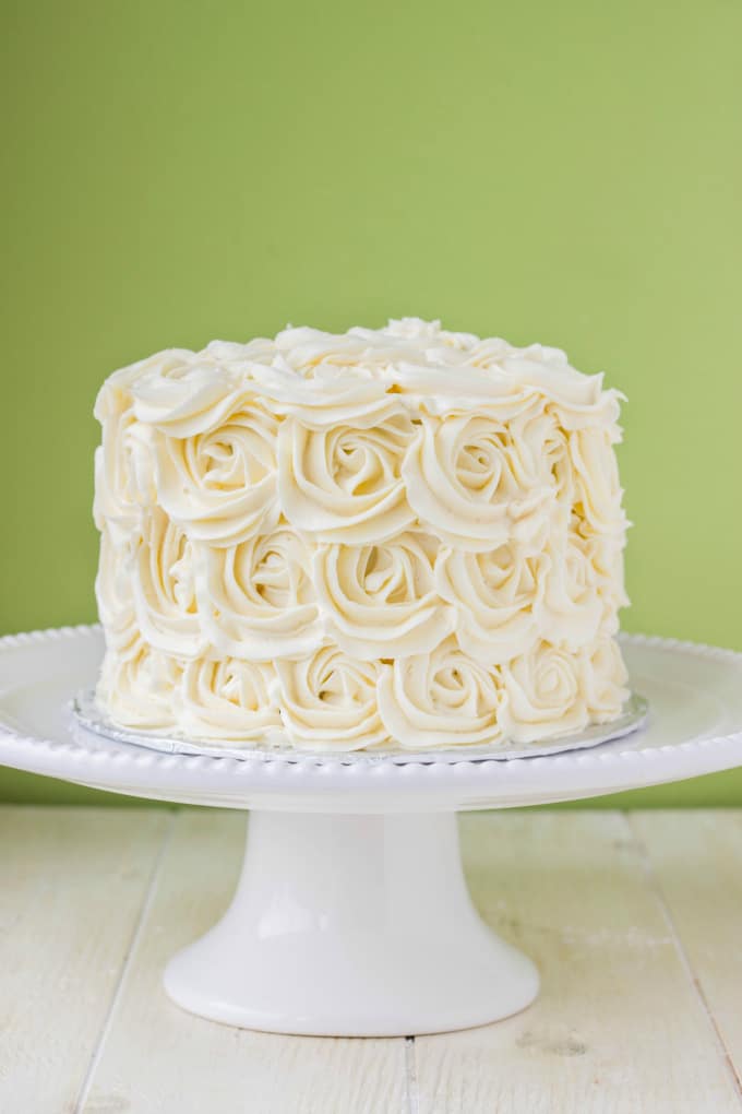 Red Velvet Cake with Vanilla Buttercream Rosettes on white tray on white table on green background