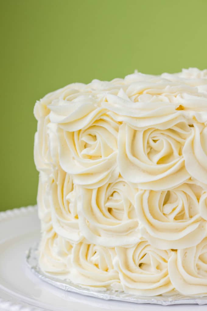 Red Velvet Cake with Vanilla Buttercream Rosettes on white tray, green background