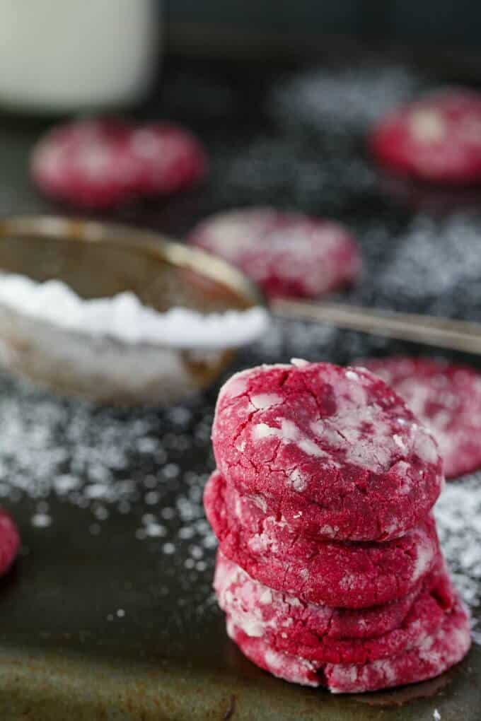 Red Velvet Cookie Crinkles on black table with sprinkler with sugar