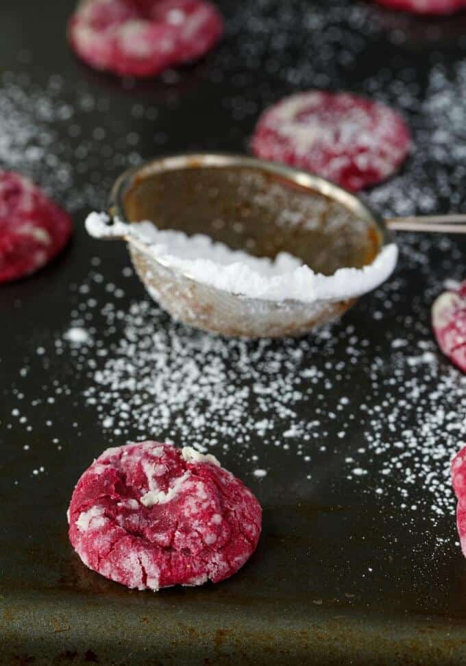 Red Velvet Cookie Crinkles on black table with sprikles with sugar