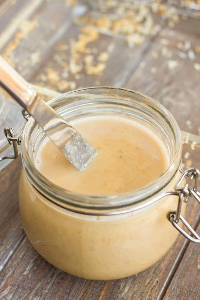 Toasted Coconut Butter in glass jar with knife on wooden table