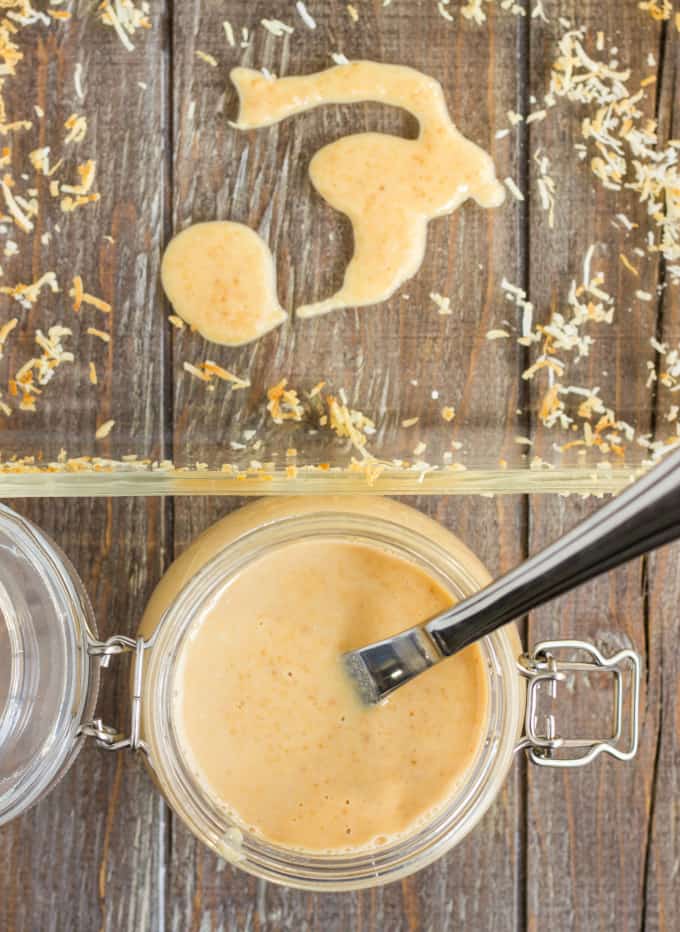 Toasted Coconut Butter in glass jar with knife on wooden table next to glass container