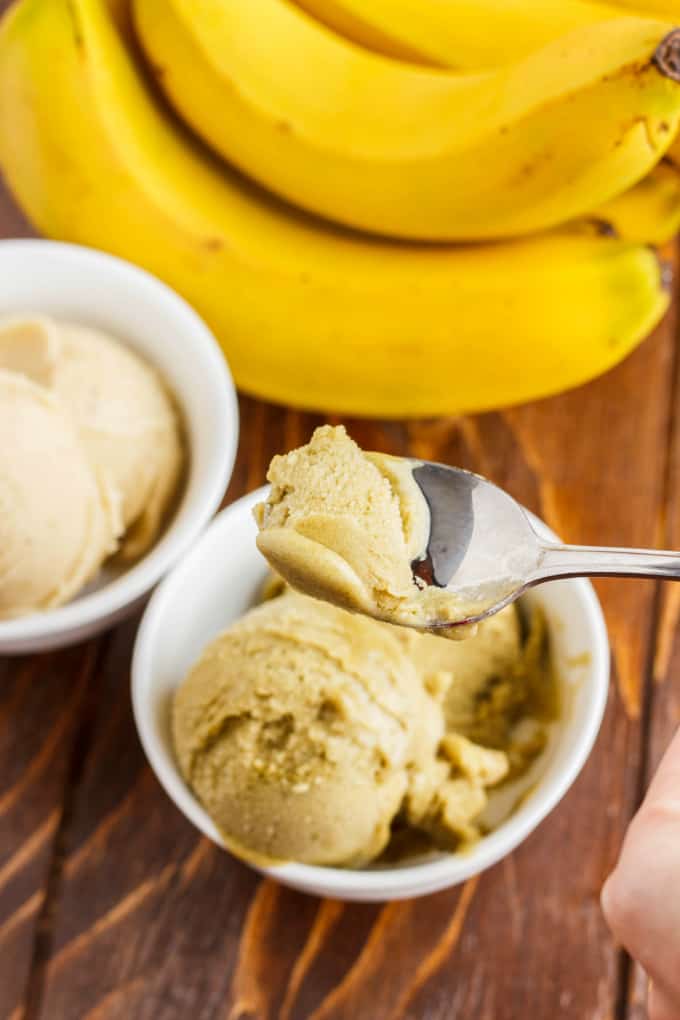 Banana Nice Cream (Banana Ice Cream) in white bowls picked by spooon on wooden table with bananas