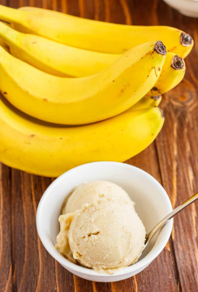 Banana Nice Cream (Banana Ice Cream) in white bowl with spoon on wooden table with bananas
