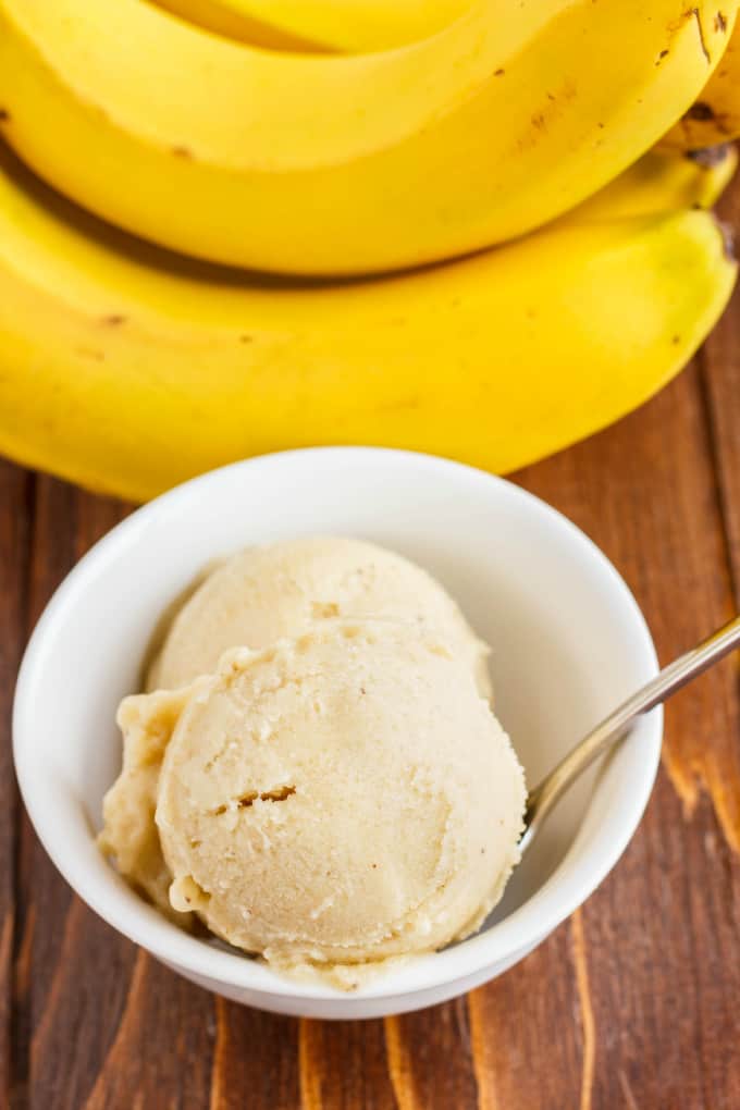 Banana Nice Cream (Banana Ice Cream) in white bowl with spoon on wooden table with bananas