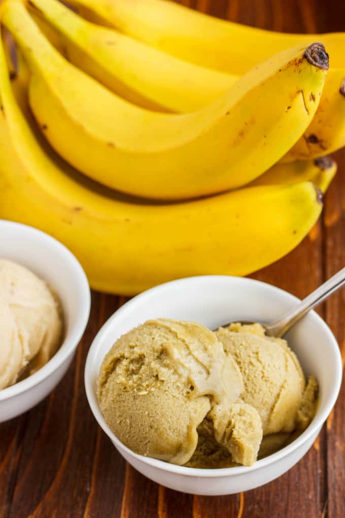 Banana Nice Cream (Banana Ice Cream) in white bowls with spoon on wooden table with bananas