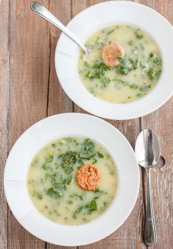 Caldo Verde Soup on white plates with spoon on wooden table