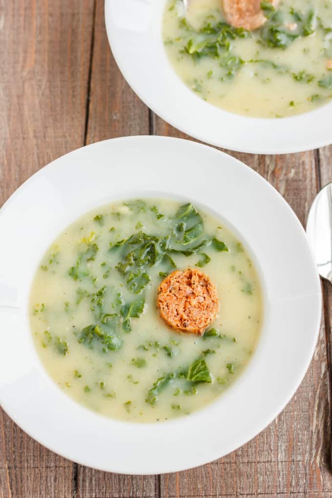Caldo Verde Soup on white plates with spoon on wooden table
