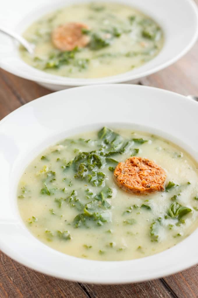 Caldo Verde Soup on white plates with spoon on wooden table