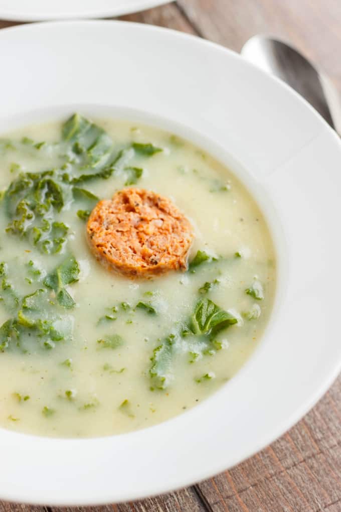 Caldo Verde Soup on white plate with spoon on wooden table