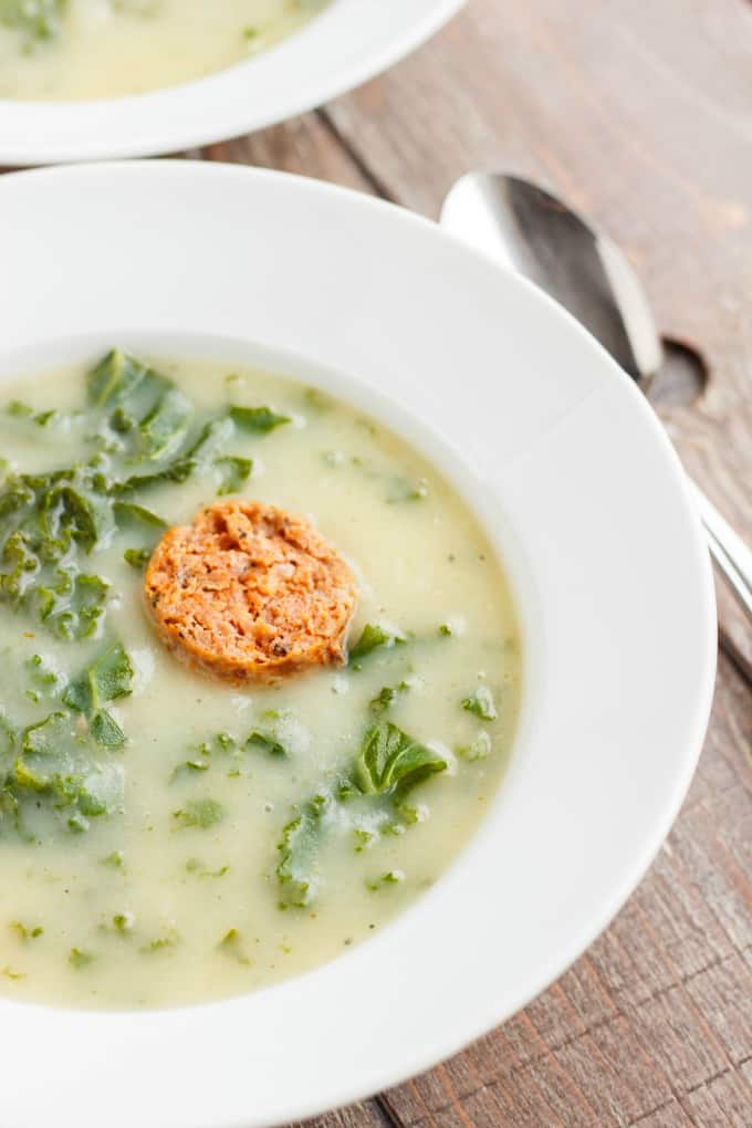 Caldo Verde Soup on white plate with spoon on wooden table