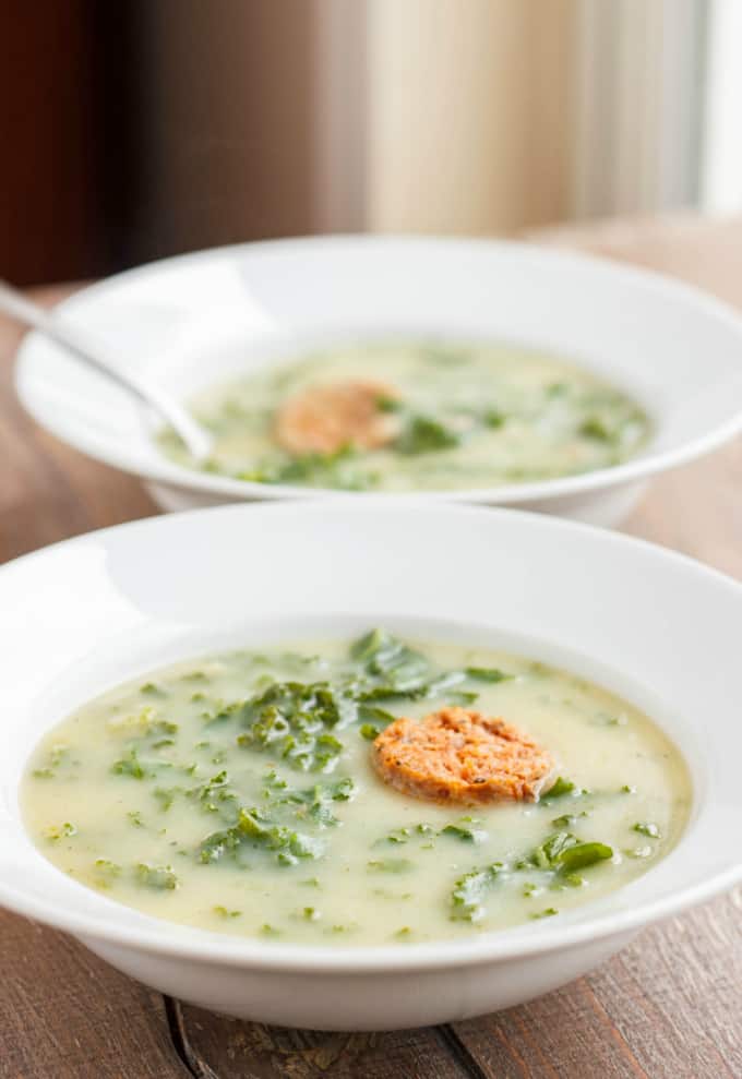 Caldo Verde Soup on white plates with spoon on wooden table