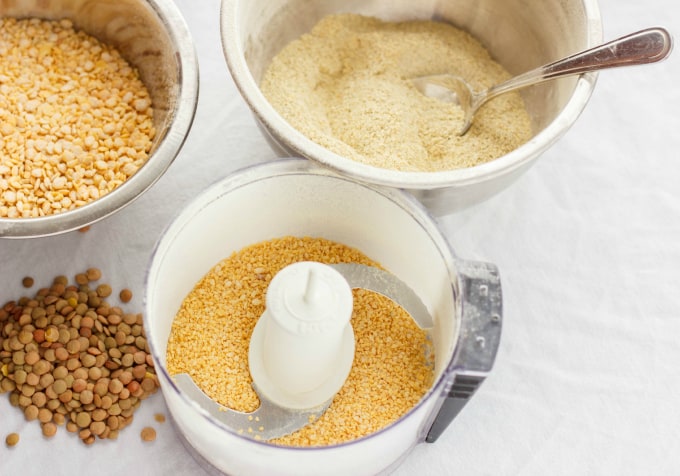 Bledner with lentils, two bowls with blended lentils and whole lentils and lentils on white table