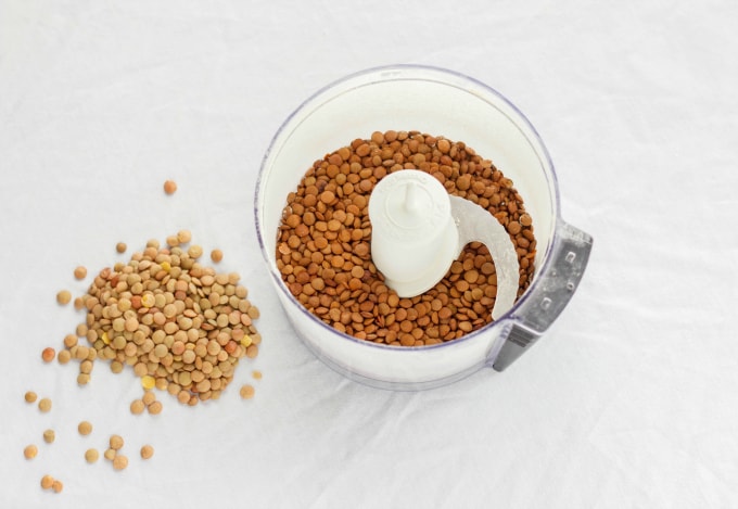 Lentil in blender on white table next to lentils 