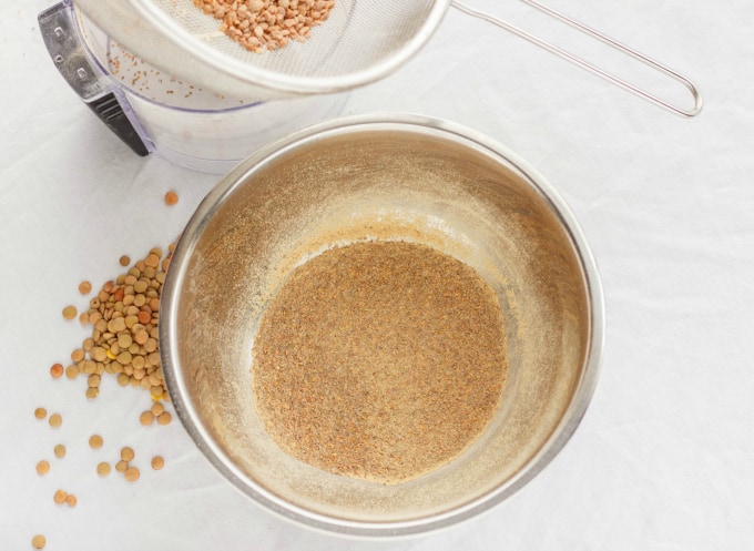 lentils in bowl and on the white table with lentils next to kitchen strainer on container