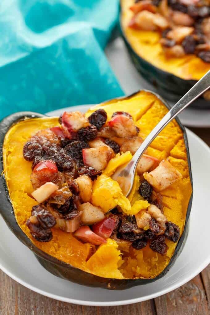 Acorn squash stuffed with apple and raisins with fork on white plate