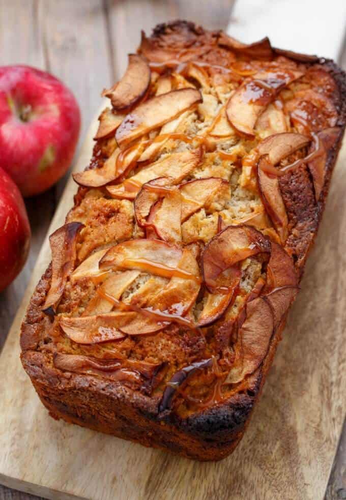 Apple Cinnamon Bread with Caramel on wooden pad next to red apples