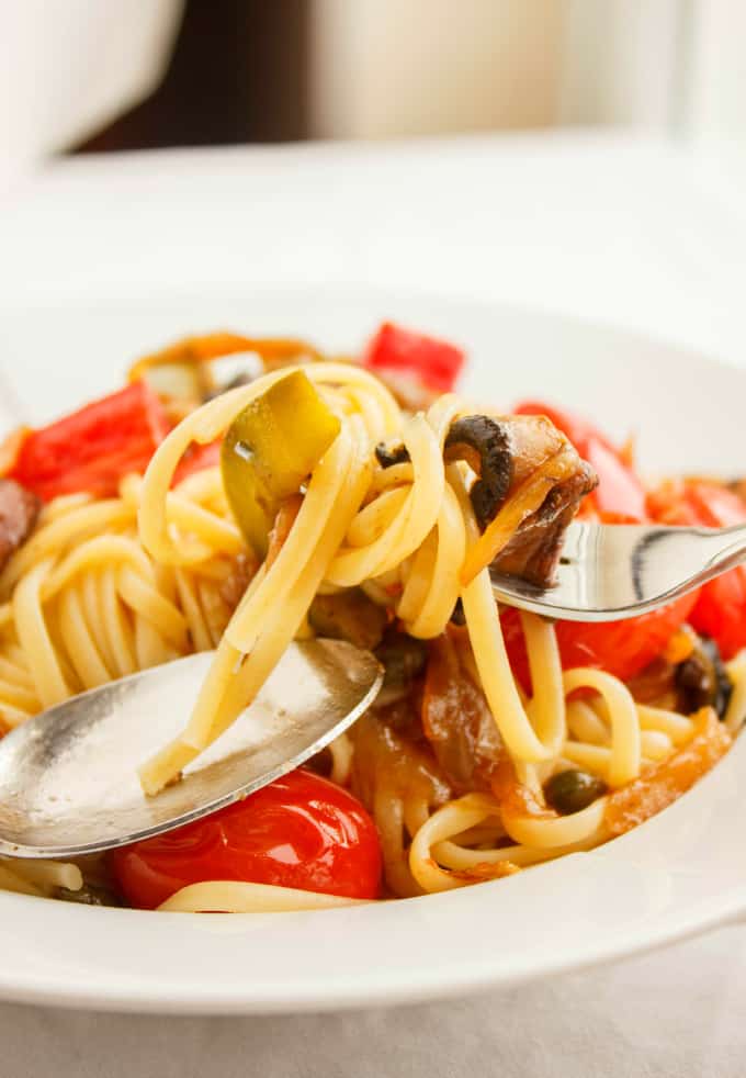 Artichoke Hearts, Caramelized Onions and Roasted Portobello Mushroom Pasta on white plate with spoon and fork