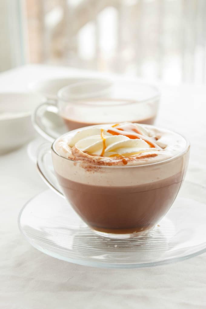 Salted Caramel Hot Cocoa in glass cups on glass plates on white table