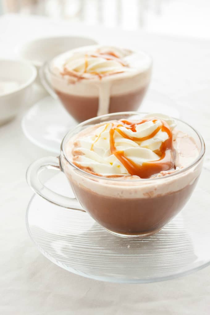 Salted Caramel Hot Cocoa in glass cups on glass plates on white table