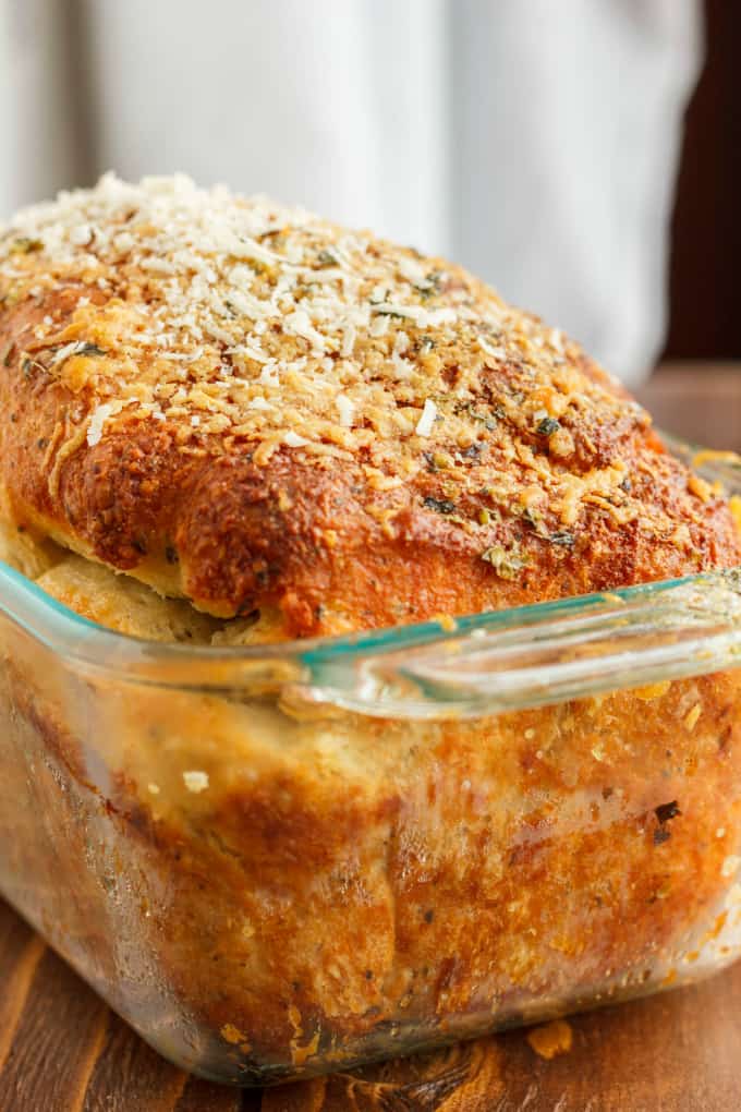 Herb and Cheese Bread loaf in cooking glass pot on wooden table