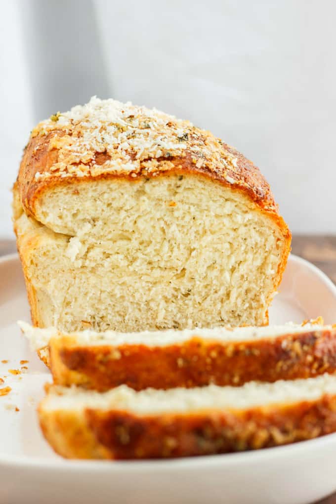 Herb and Cheese Bread loaf and two slices on white tray