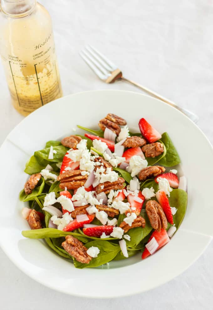 Milestones' California Spring Salad  on white plate with fork and bottle on white table