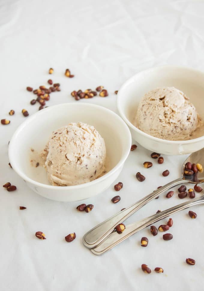 Red Bean Ice Cream in white bowls on white table with spoons and sprinkled red beans