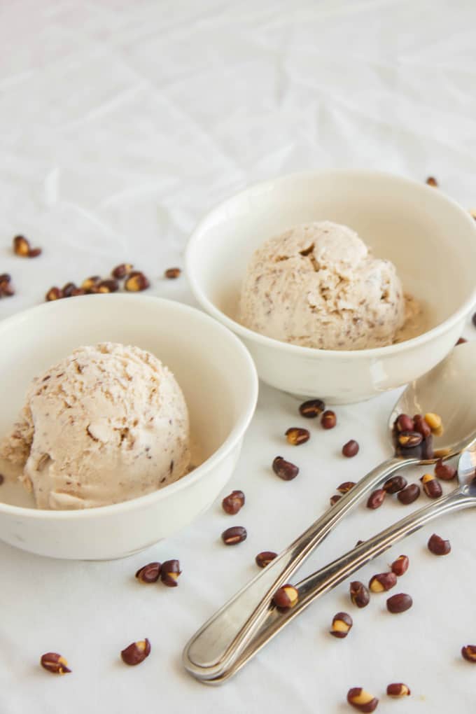 Red Bean Ice Cream in white bowls with two spoons and spilled red beans around