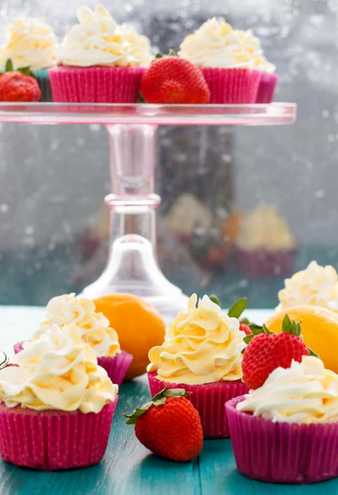 Strawberry Cupcakes with Lemon Swiss Meringue Buttercream on blue table and glass tray with ripe strawberries and lemons#dessert