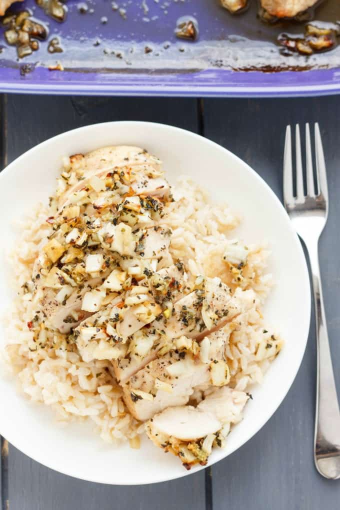 Sweet Garlic Chicken Breasts on white plate next to fork and purple baking pot #garlic