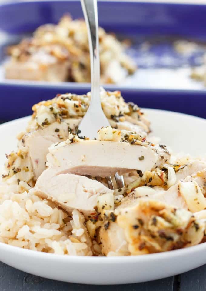 Sweet Garlic Chicken Breasts picked by fork on white plate, purple baking pot in the background#glutenfree