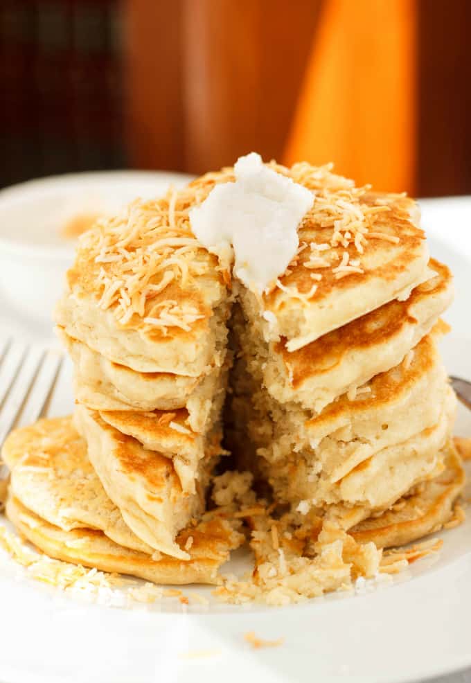 Toasted Coconut Pancakes with cream on top on white plate