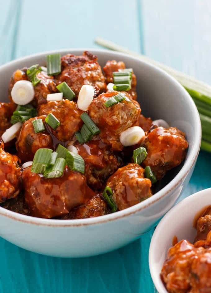 General Tso's Meatballs in white bowls on blue table with veggies#appetizer