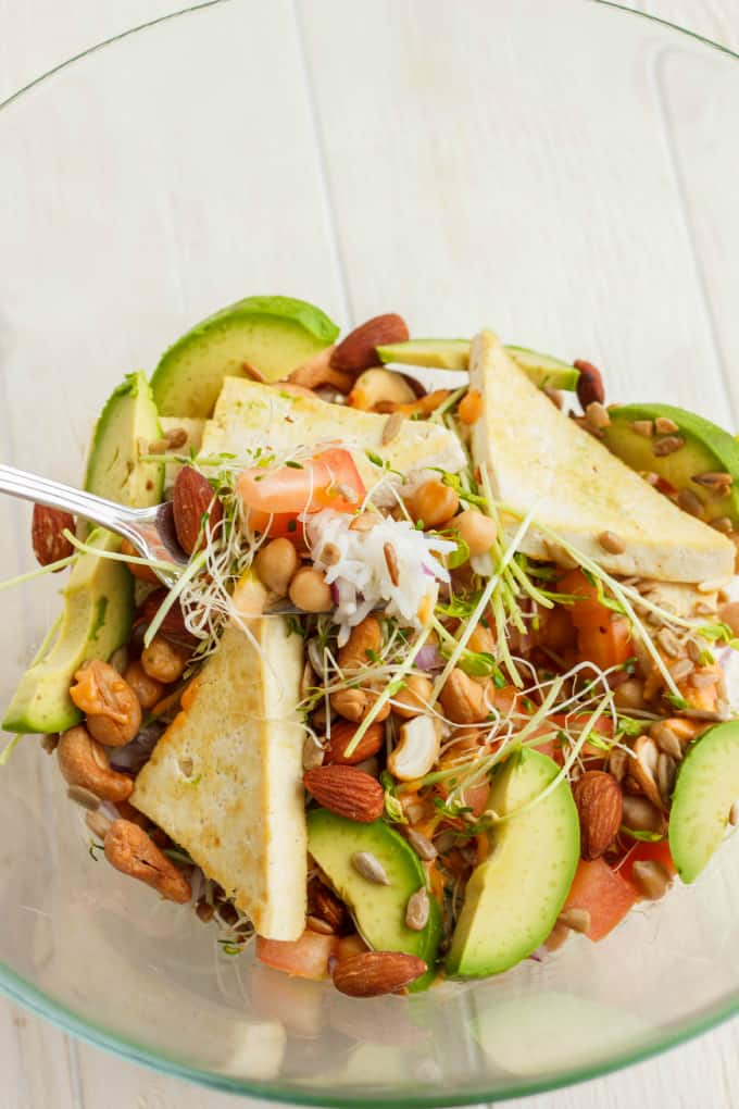 Fresh Powerhouse  in glass Bowl with fork, many veggies, fruits, nuts and bread