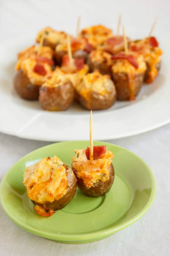 Jalapeno Popper Stuffed Creamer Potatoes on small green plate and on white plate in the background