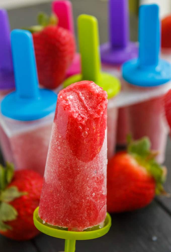 Strawberry Sorbet Popsicles , in the background popsicles in plastic forms with ripe strawberries